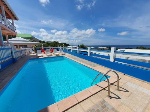 a swimming pool on a balcony with the ocean in the background at Villa Oceane in Le Moule