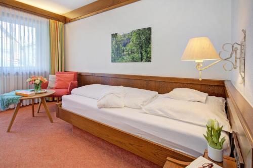 a bedroom with a large bed and a red chair at Hotel Restaurant Falken in Baiersbronn