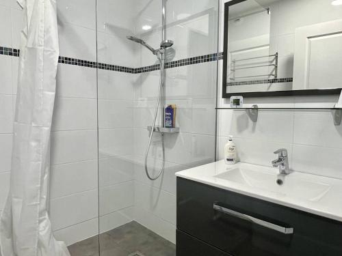une salle de bain blanche avec une douche et un lavabo dans l'établissement Confort à Cambo : T2 pour 2 pers., balcon-terrasse, cuisine équipée, parking, accès internet - FR-1-495-133, à Cambo-les-Bains