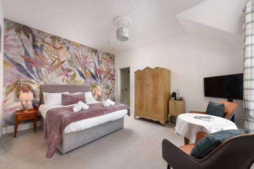 a bedroom with a large bed with a large painting on the wall at Strathardle Lodge in Kirkmichael