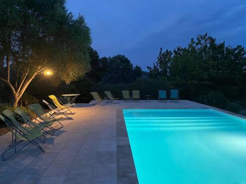 - une piscine avec des chaises et une table la nuit dans l'établissement Mas provençal dans un vignoble, à La Motte