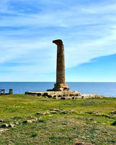 a stone monument in a field near the ocean at Il Vico del Greco B&B in Le Castella