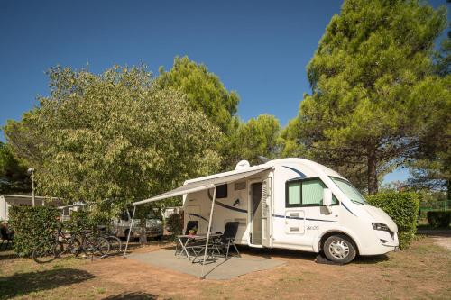 a small white caravan parked in a park at Maistra Camping Porto Sole Pitches in Vrsar