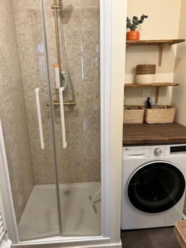 une douche dans une salle de bain avec machine à laver dans l'établissement L'écume des jours VUE MER, à Dieppe