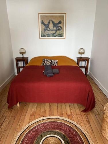 une chambre avec un lit avec une couverture rouge dans l'établissement L'écume des jours VUE MER, à Dieppe