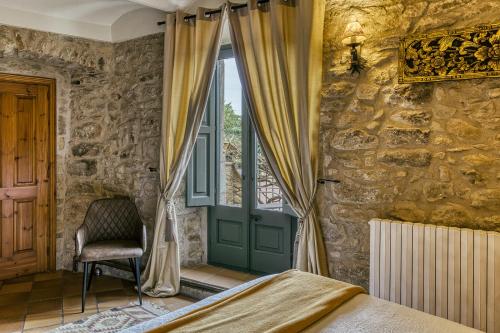 a bedroom with a bed and a window and a chair at El Racó de Madremanya - Adults only in Madremanya