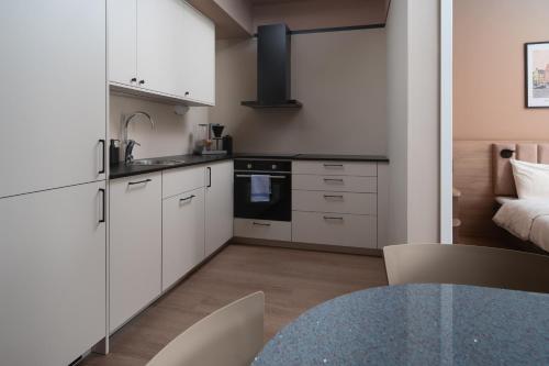 a kitchen with white cabinets and a table and a bed at Sky Hotel Apartments, Stockholm in Stockholm