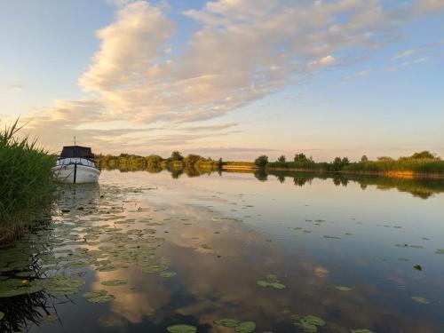 ein Boot auf einem Fluss mit wolkigem Himmel in der Unterkunft Jono Bulavino sodyba in Mingė