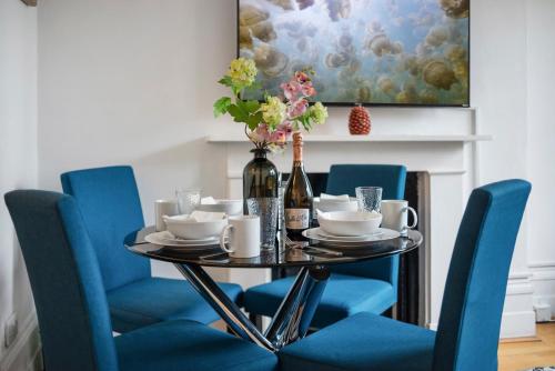 ein Esszimmer mit blauen Stühlen und einem Tisch mit Weinflaschen in der Unterkunft Modern Living in the Heart of Covent Garden! 6BC in London