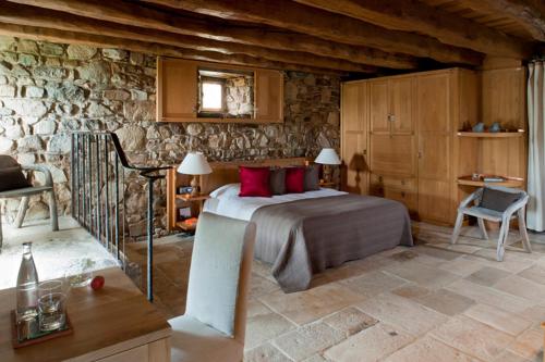 MassignacにあるHOTEL Domaine des Etangs, Auberge Resorts Collectionの石壁のベッドルーム1室(ベッド1台付)