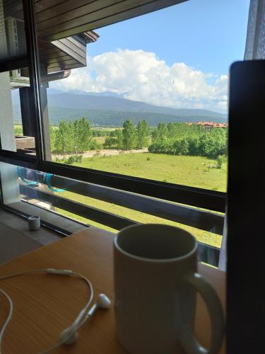 F307 Studio Aspen Golf Resort Bansko في بانسكو: وجود كوب قهوة على طاولة أمام النافذة