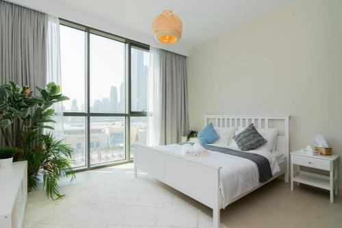 a white bedroom with a bed and a large window at Elite Escape Holiday Home - 2 BHK Getaway with Dubai Mall Access - 1503 in Dubai