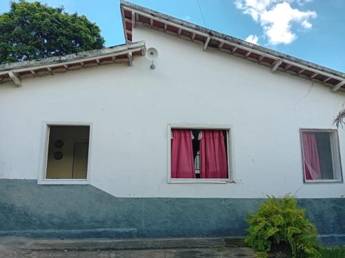 Casa Delicia em Passa Quatro Até 4 pessoas في باسا كواترو: منزل أبيض مع ستارة حمراء في النافذة