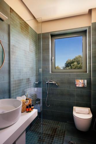 a bathroom with a sink and a toilet and a window at LILY'S VILLA LEMONIA in Platanes