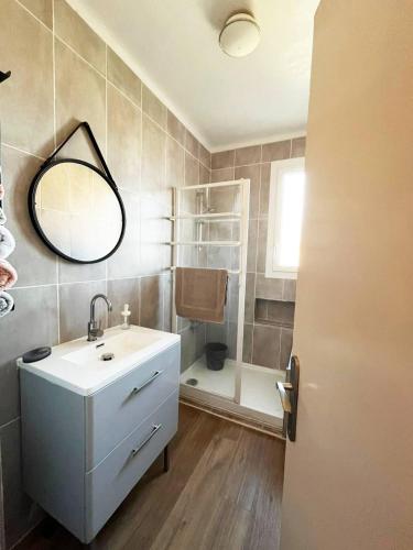 a bathroom with a sink and a shower with a mirror at Merveilleux appartement style nature proche centre ville in Collioure