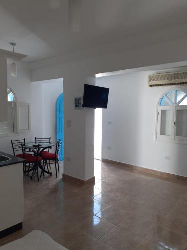 ein Wohnzimmer mit einem Tisch und einem TV an der Wand in der Unterkunft monolocale a Sharm el Sheikh in Sharm El Sheikh