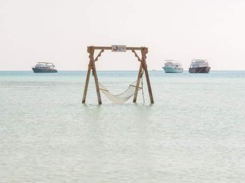 a hammock in the middle of the water with boats at orange bay in Hurghada