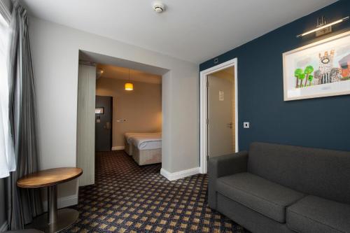 een hotelkamer met een bank en een bed bij The King's Head Hotel Wetherspoon in Beccles