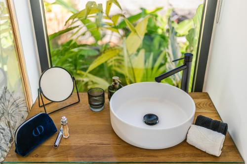 un lavandino da bagno su un bancone in legno con specchio di L'Empreinte-Oasis de Sérénité au Coeur d'un jardin tropical a Le Tampon