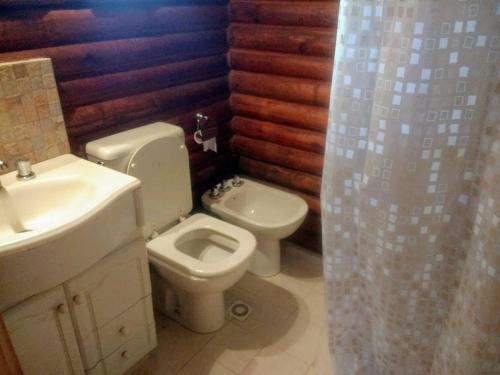a bathroom with a toilet and a sink and a shower curtain at CABAÑA EN EL MANZANO HISTORICO in Los Árboles