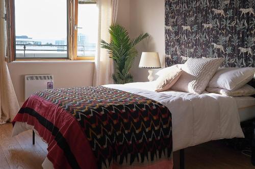 a bedroom with a bed with a blanket on it at Sunny Shoreditch Oasis Canal Views & Urban Charm in London