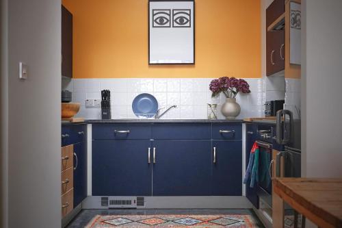 a kitchen with blue cabinets and a vase of flowers at Sunny Shoreditch Oasis Canal Views & Urban Charm in London