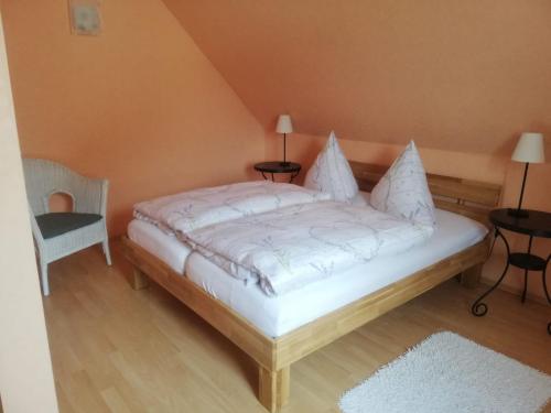 um quarto com uma cama branca e uma cadeira em Ferienwohnung 1 Schulze em Neustrelitz