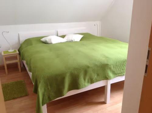 Una cama verde con dos almohadas encima. en Ferienwohnung 2 Schulze, en Neustrelitz