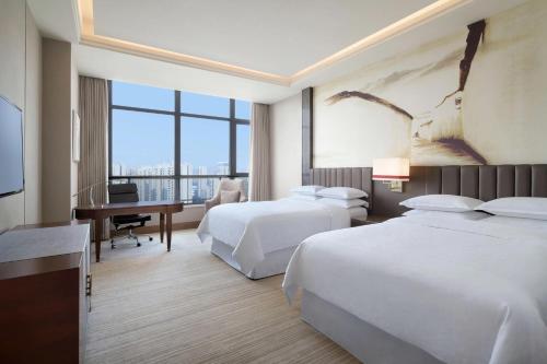 a hotel room with two beds and a desk at Sheraton Chuzhou Hotel in Chuzhou