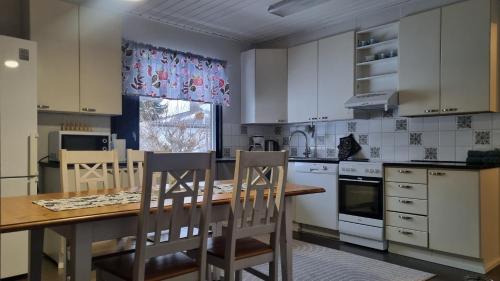 une cuisine avec des placards blancs et une table et des chaises en bois dans l'établissement 3 bedrooms, sauna and kitchen All house, à Pori