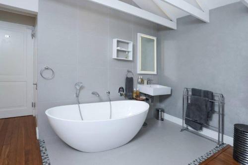 a large white tub in a bathroom with a sink at Onrus Beach House in Hermanus