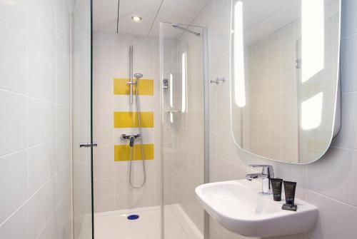 a bathroom with a shower and a sink and a mirror at Hotel Mercure Château de Fontainebleau in Fontainebleau