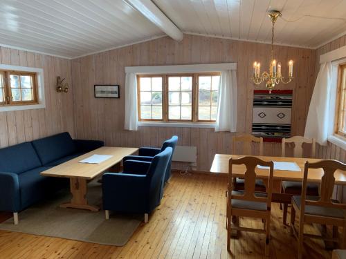a living room with a table and a blue couch at Tyinholmen Høyfjellsstuer in Eidsbugarden