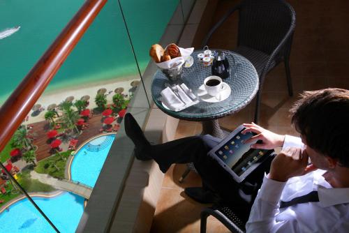 a woman is sitting at a table with a laptop at Khalidiya Palace Rayhaan by Rotana, Abu Dhabi in Abu Dhabi