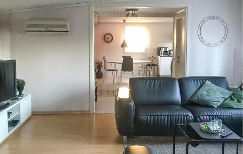 a living room with a black leather couch and a kitchen at 3 Bedroom Cozy Home In Mönsterås in Mönsterås