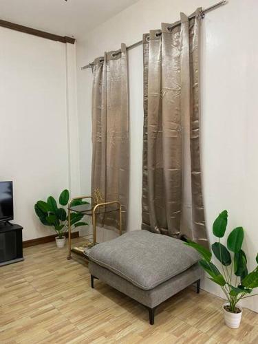 - un salon avec une chaise et des rideaux dans l'établissement Balai ni Atan - relaxing studio unit near airport, à General Santos