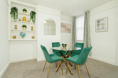 a dining room with a glass table and green chairs at Immaculate 3-Bed House in Chatham in Chatham