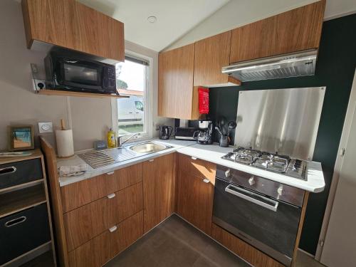 a small kitchen with a stove and a sink at Jolie Mobil home 2 chambres (198) in Saint-Jean-de-Monts