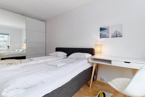 a white bedroom with a large bed and a desk at Bergen's Finest: Sleek Oasis with Two Bedroom in Bergen