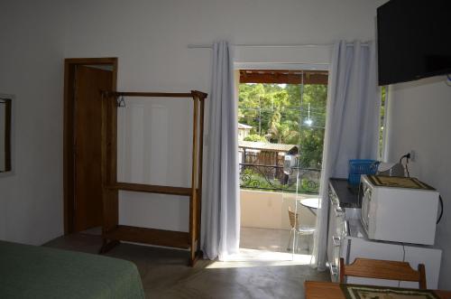 a bedroom with a door open to a balcony at Suítes Paquetá Ilhabela in Ilhabela