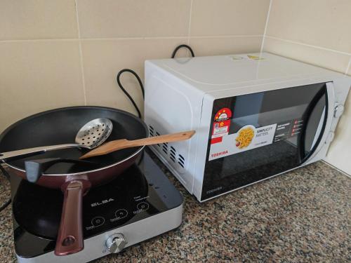 a frying pan and a pot on a toaster oven at Homestay Pangsapuri Simfoni 3BR 7Pax Kuah Langkawi in Kuah