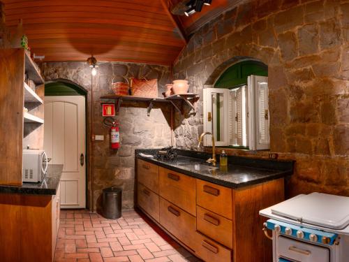 a kitchen with a sink and a stone wall at Casa de Pedra Mena Kaho in Bento Gonçalves