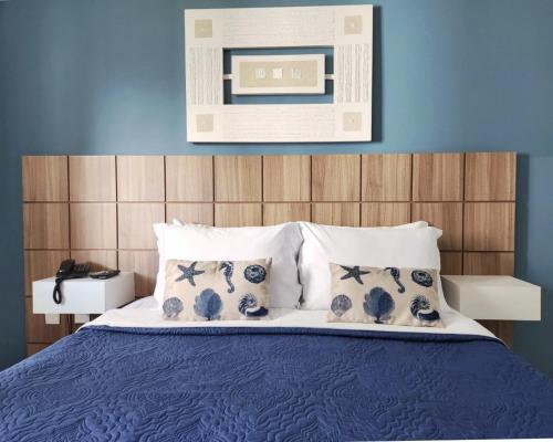 a bedroom with a blue wall and a bed with pillows at Apartamento Barra Pé na Areia in Rio de Janeiro