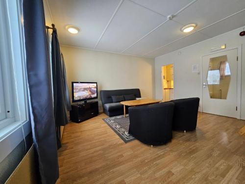 uma sala de estar com uma mesa e cadeiras e uma televisão em Lofotr Overnatting em Bøstad