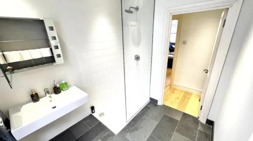 ein weißes Bad mit einem Waschbecken und einer Dusche in der Unterkunft Mayfair Stylish central London Modern Suite in London