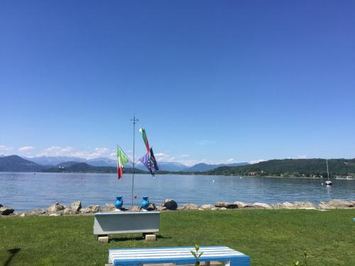 una panchina con tre bandiere accanto a un corpo d'acqua di Bnbook Lago Maggiore Studio a Castelletto sopra Ticino