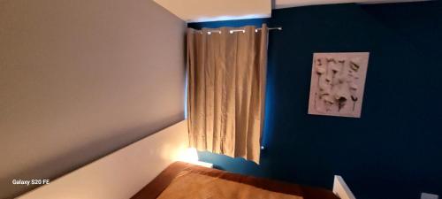 a bedroom with a blue wall with a curtain at Nice and Pleasant in Thornton Heath