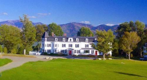 a large white house with mountains in the background at Sunset Hill House in Sugar Hill