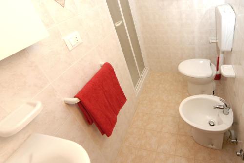 La salle de bains est pourvue de toilettes et d'une serviette rouge. dans l'établissement Family comfort in Bibione - Beahost, à Bibione