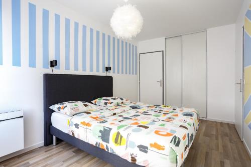 1 dormitorio con 1 cama con un edredón colorido en Appartement Cosy Près de Paris avec vue sur la Tour Eiffel - Parking & Wifi, en Argenteuil